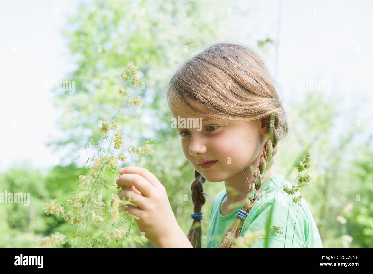 Germany, Bavaria, Munich, Girl holding flower, smiling Banque D'Images