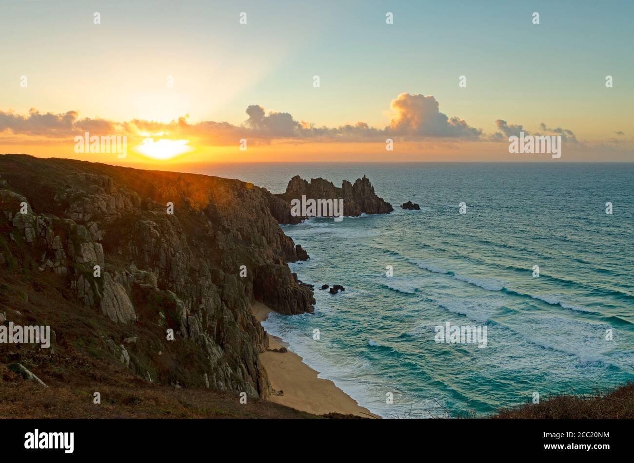 le lever du soleil se brise sur le rocher de logan et la plage de pedn vounder à proximité porthcurno dans l'extrême ouest des cornouailles Banque D'Images