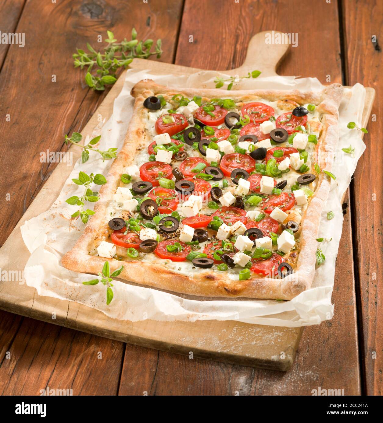 Tarte avec tranche de tomate et fromage feta sur planche à pizza Banque D'Images