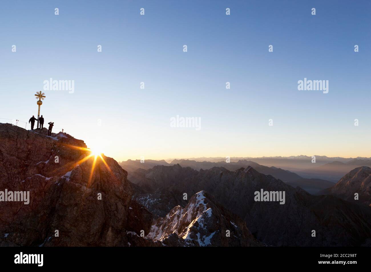 Allemagne, Bavière, Alpes bavaroises, Wetterstein Range, vue de croix sur le sommet de Zugspitze avec des randonneurs au lever du soleil Banque D'Images