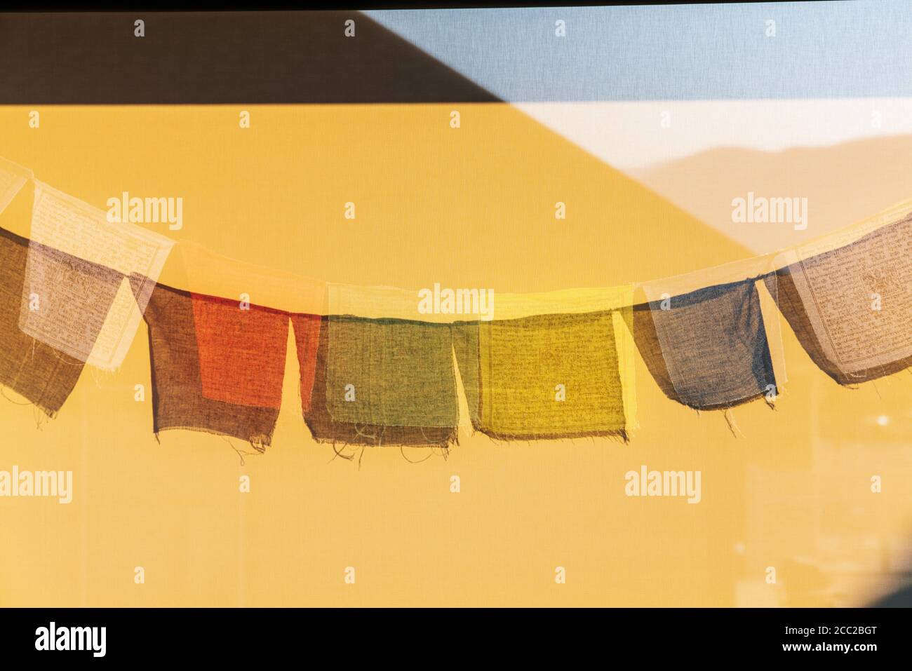 Le soleil projette des ombres des drapeaux de prière bouddhistes traditionnels sur un pare-vent Banque D'Images