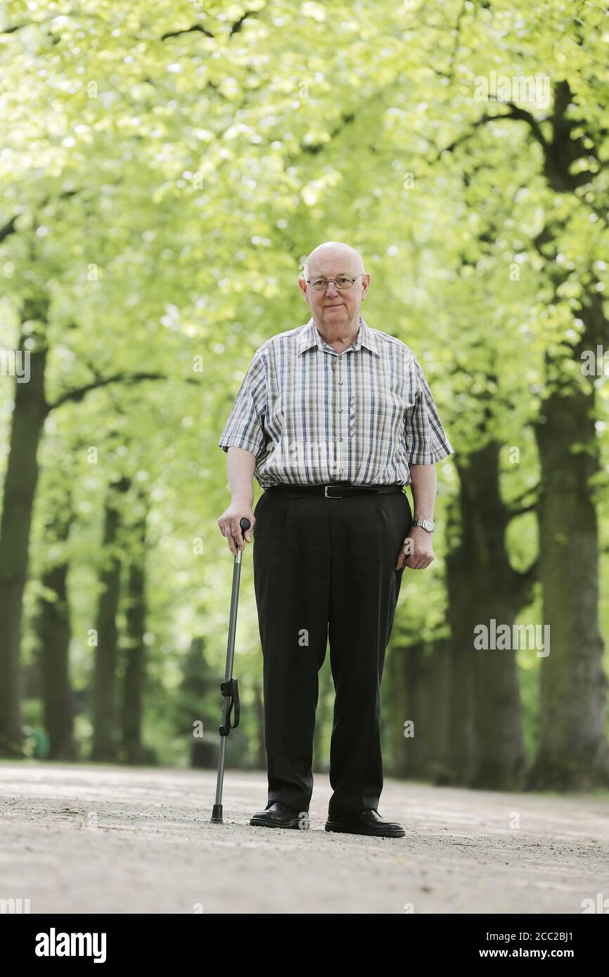 L'Allemagne, en Rhénanie du Nord-Westphalie, Cologne, Portrait of senior man with walking stick en parc, smiling Banque D'Images