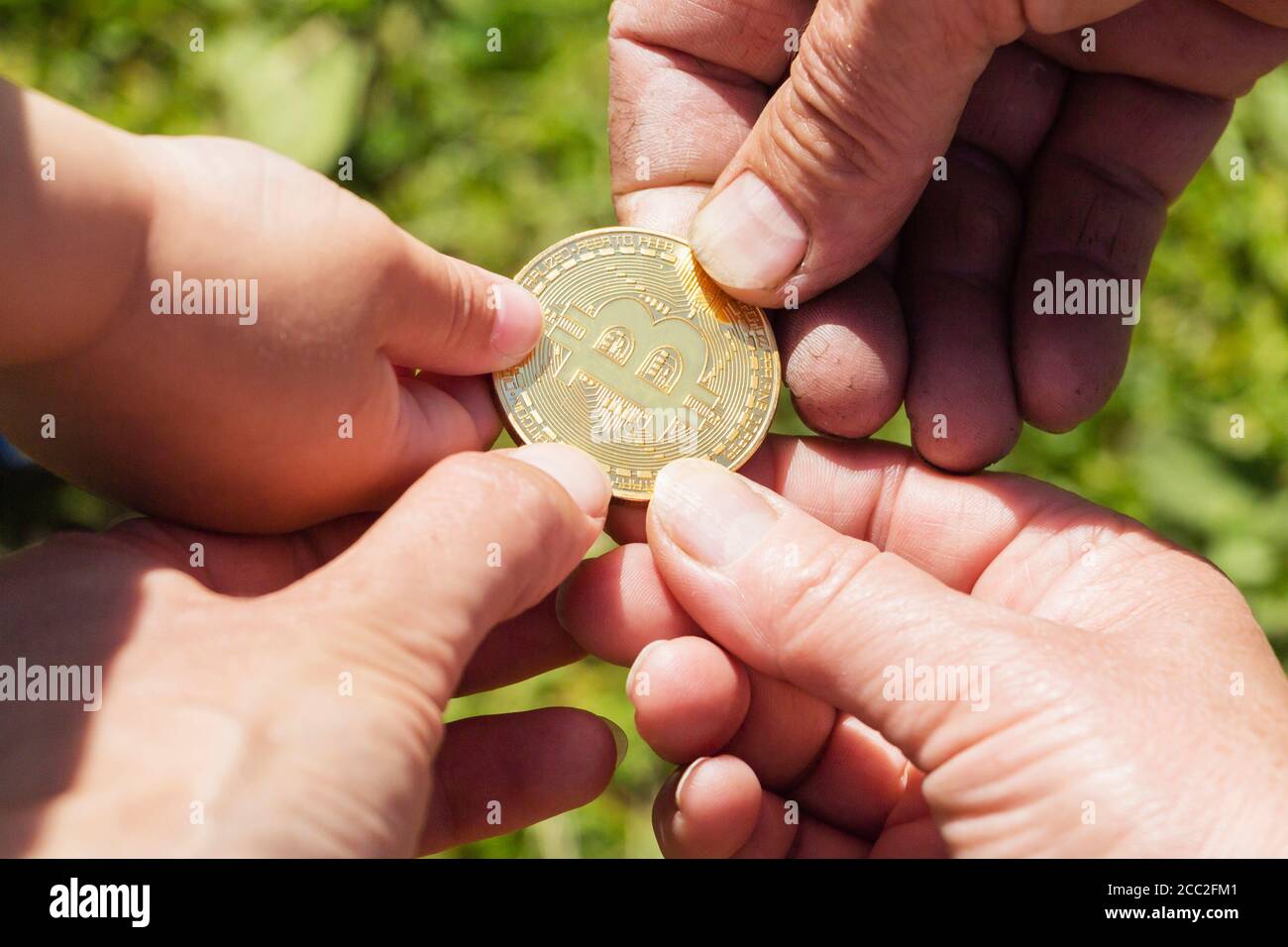 Mains de différentes personnes tenant une pièce de monnaie en or bitcoin. Arrière-plan flou. Banque D'Images