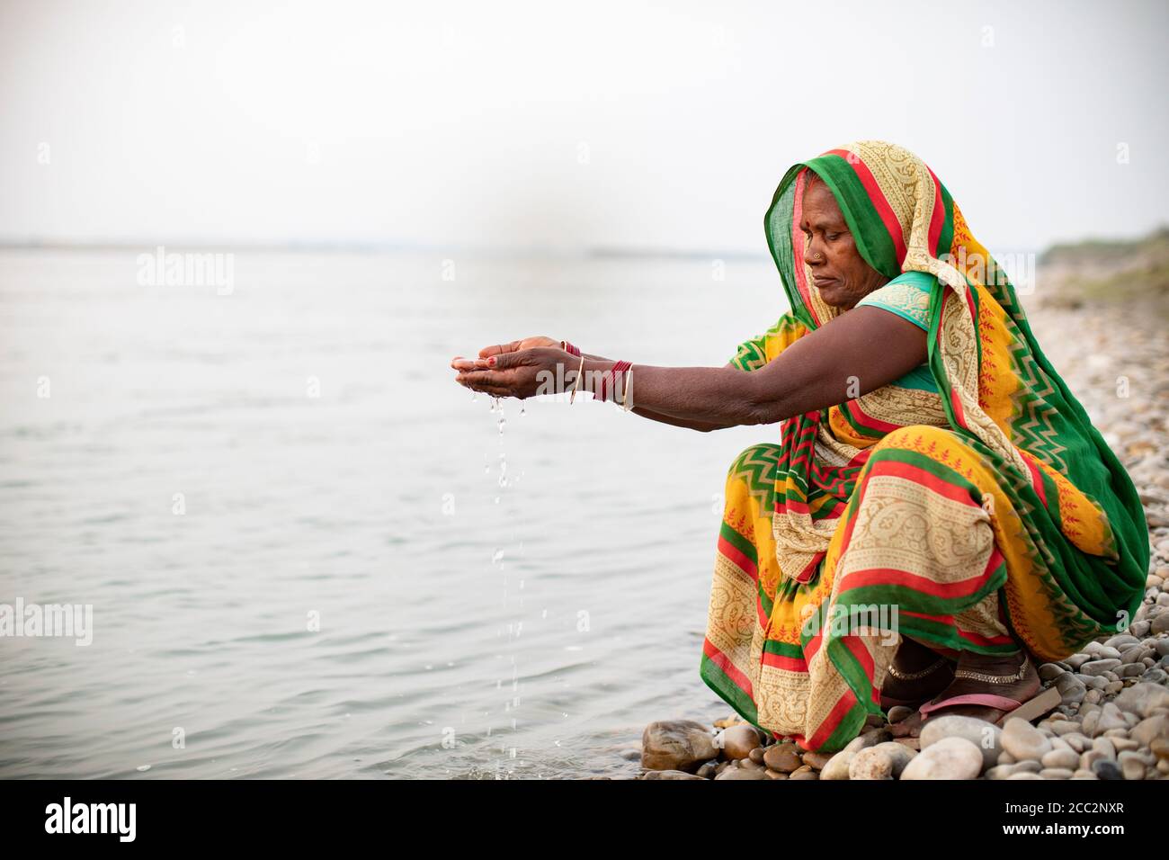 Une femme prie le long des rives de la rivière Gandak à Bihar, en Inde. Les hindous prient souvent sur les berges et les rives, car l'eau est considérée comme sainte. Banque D'Images