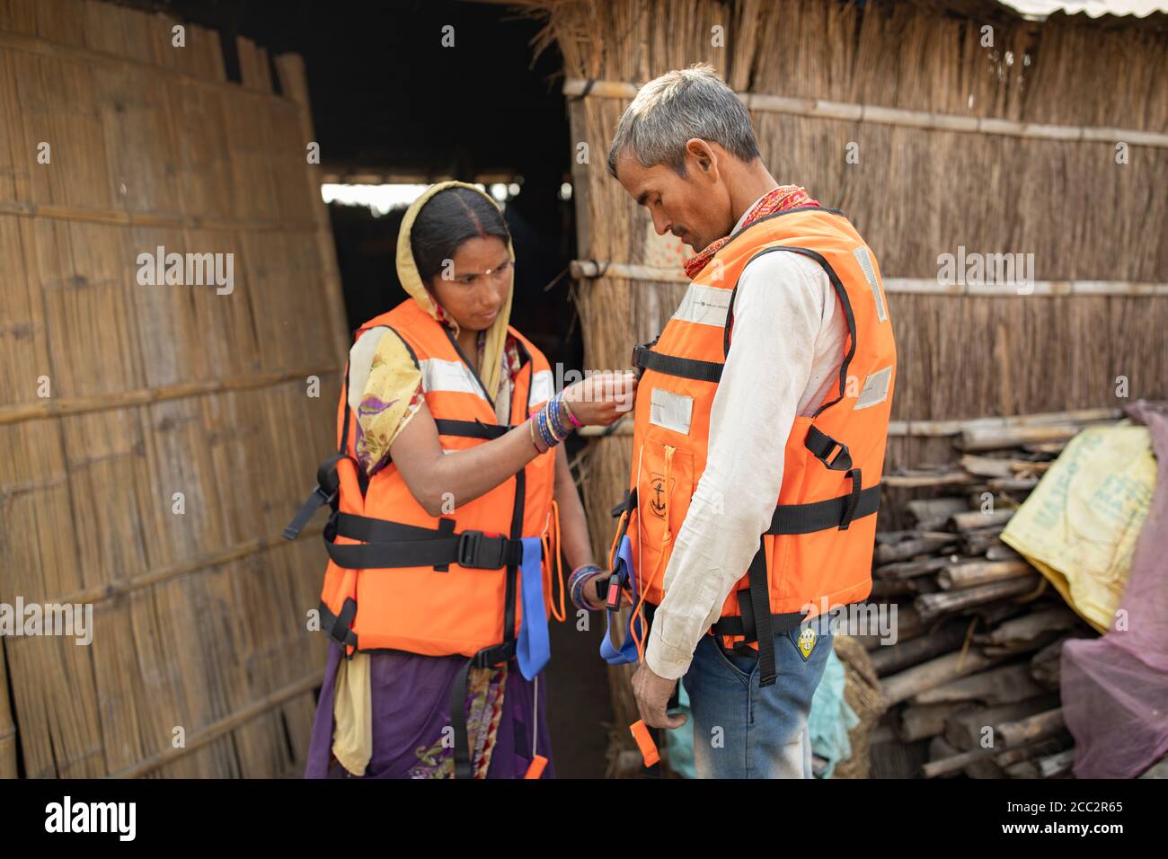 Une femme et son mari ont enfilé des gilets de sauvetage dans un exercice de préparation aux inondations à l'extérieur de leur maison dans le district de Champaran Ouest, Bihar, Inde. Des gilets de sauvetage sont fournis à leurs communautés et à d’autres communautés susceptibles d’être inondées dans les bassins fluviaux de Gandak et de Koshi le long de la frontière entre le Népal et l’Inde dans le cadre du projet de résilience aux crues transfrontières du LWR. Banque D'Images