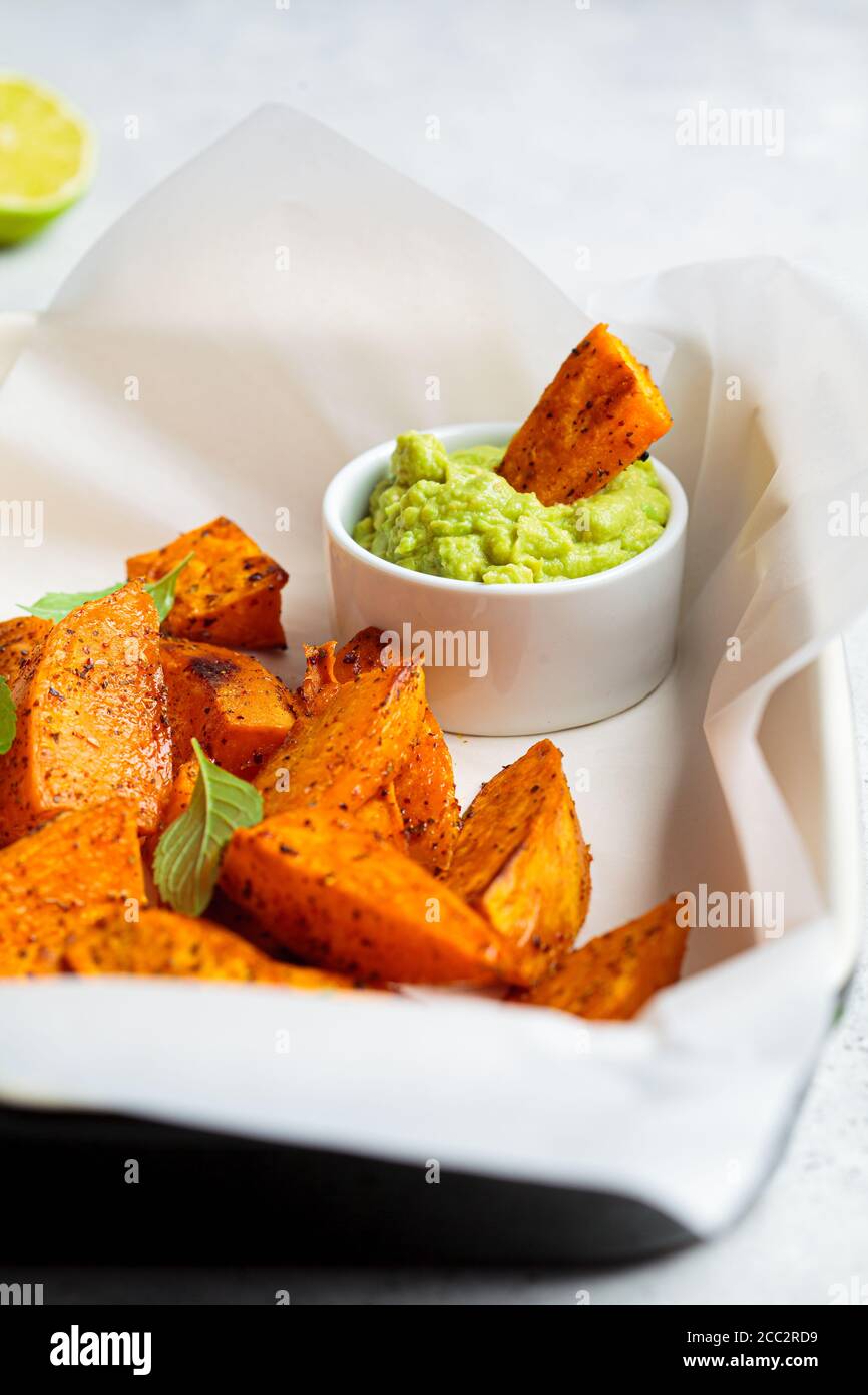 Quartiers de patates douces cuits avec sauce à l'avocat. Concept alimentaire végétalien sain. Banque D'Images