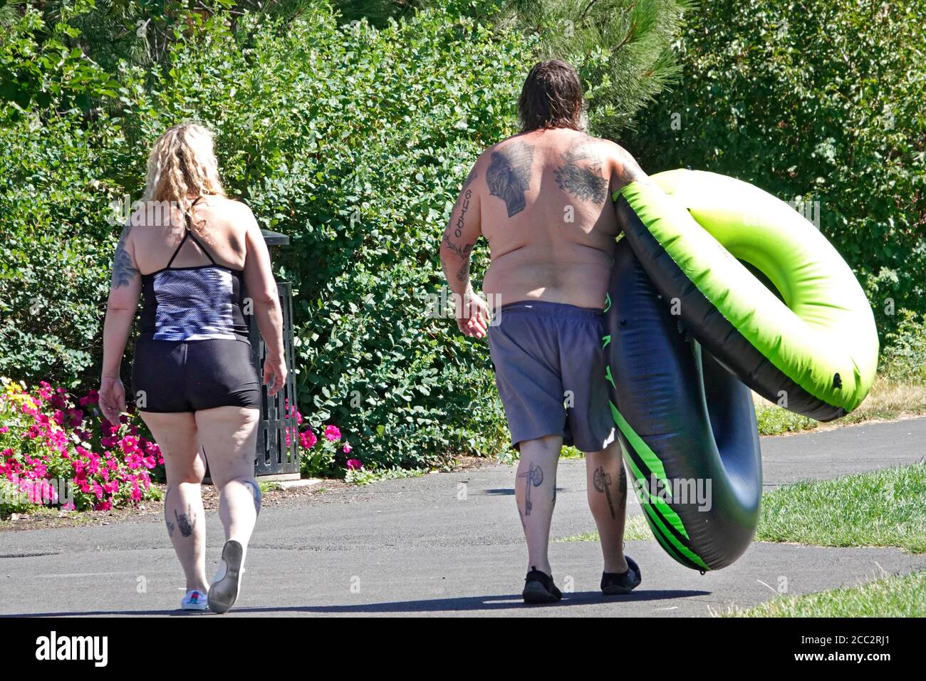 Un couple obèse se promènce sur un chemin au bord de la rivière Deschutes à Bend, Oregon. Ils ont été le tubing de la rivière et sont de retour à leur voiture Banque D'Images