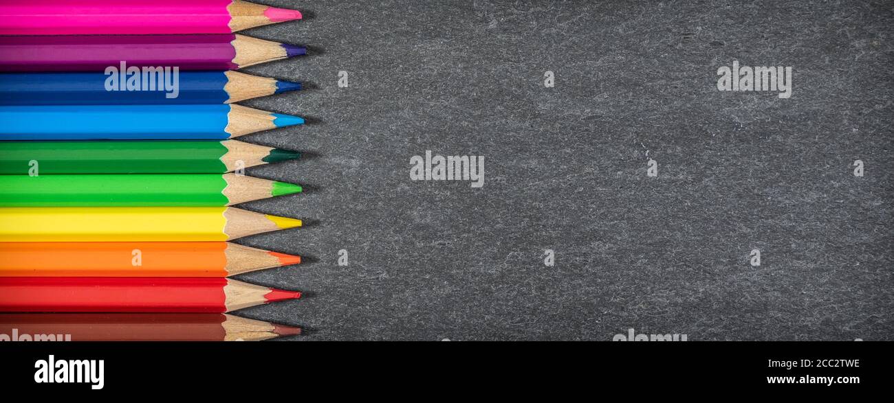 Bordure des crayons de couleur sur fond noir. Concept scolaire. Banque D'Images