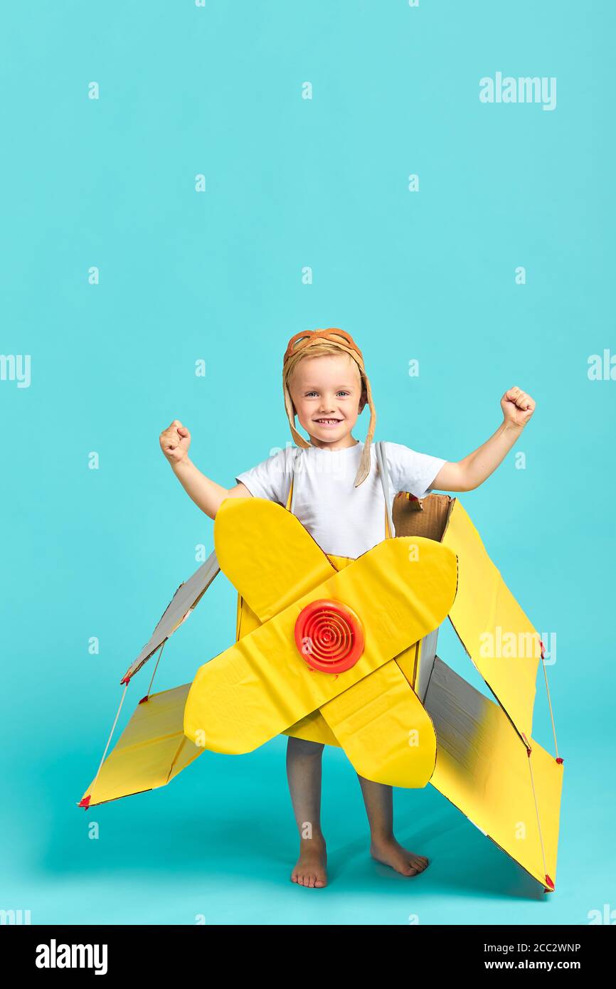 Enfant dans l'avion jaune jouet montrer des muscles à la caméra, la puissance de l'enfant. Imagination, fantaisie, rêves Banque D'Images