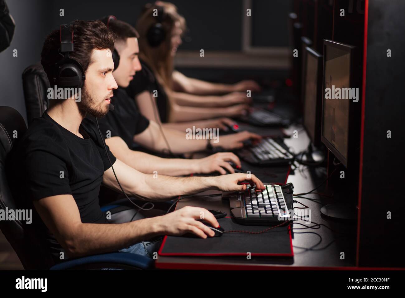 Groupe de gamers hommes et femmes adultes assis dans une rangée derrière  les moniteurs, jouer dans le centre de jeu de PC, tous équipés de souris de  jeu spéciale, clavier Photo Stock -