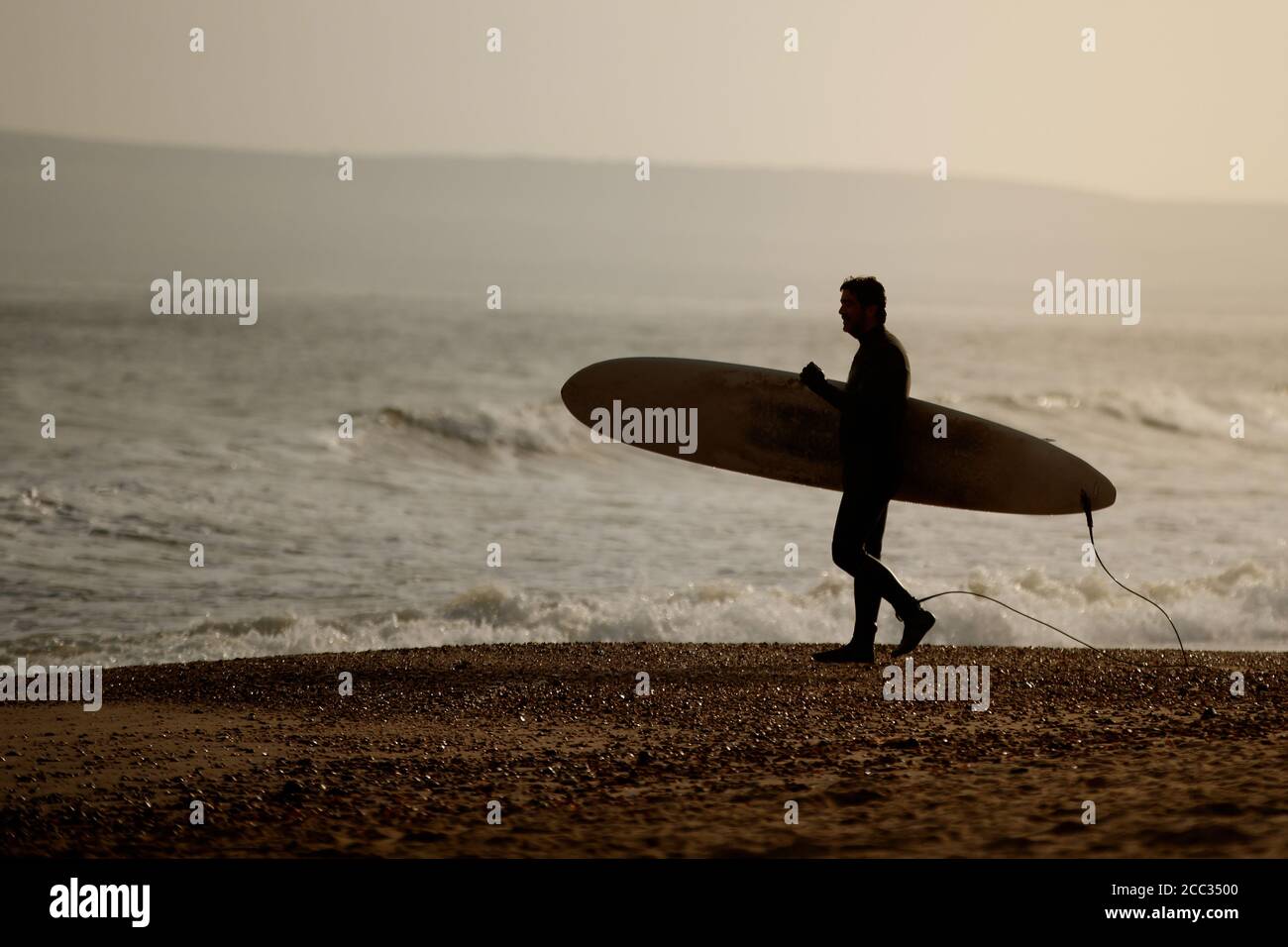 Silhouette d'un surfeur portant une planche de surf Banque D'Images
