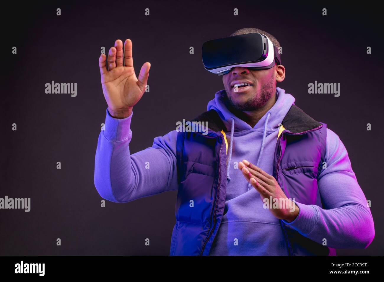 Jeune Homme A La Peau Sombre Habille De Vetements D Exterieur Ayant Sur La Tete Casque De Realite Virtuelle Mobile Pour Jouer A Des Jeux En 3d Mais A L Humanite Rencontre Une Nouvelle