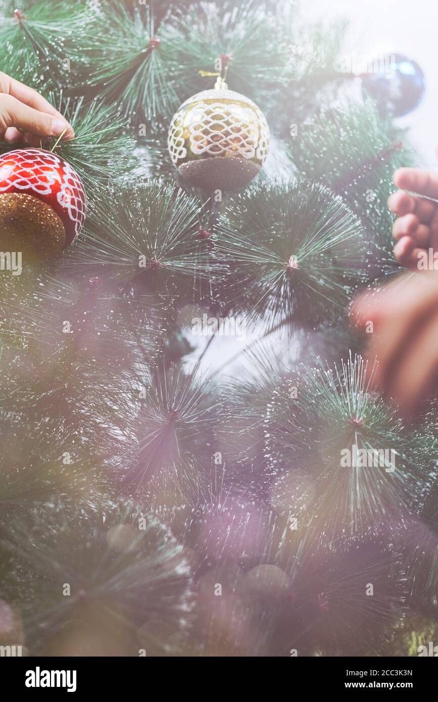 Petit enfant décorant arbre de Noël. Garçon tenant Noël orné. Arrière-grouind de Noël Banque D'Images
