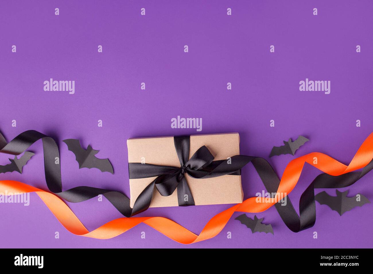 Boîte cadeau Halloween avec ruban et décoration en papier sur fond violet traditionnel. Concept de fête de Noël, d'anniversaire, d'Halloween, saisonnier Banque D'Images