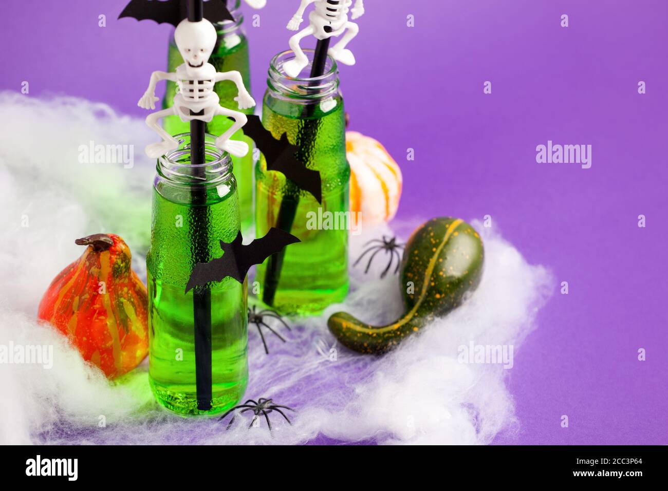 Composition Halloween avec boisson festive, cocktail vert toxique avec décor de fête effrayant et citrouilles, toile d'araignée sur fond violet traditionnel, copie Banque D'Images