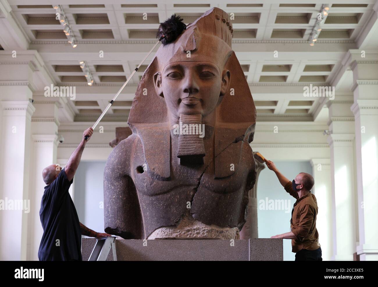 Evan York (à gauche) et Alex Truscott, responsables de la collection, ont dépoussiéré la partie supérieure d'une statue colossale assise du roi Ramsès II (vers 1279-1213 av. J.-C.), dans la galerie de sculptures égyptiennes du British Museum, Londres, alors qu'ils se préparent à rouvrir au public le 27 août après l'enfermement du coronavirus. En prévision de sa réouverture, le British Museum s'est lancé dans le plus grand programme de nettoyage depuis des décennies. Banque D'Images
