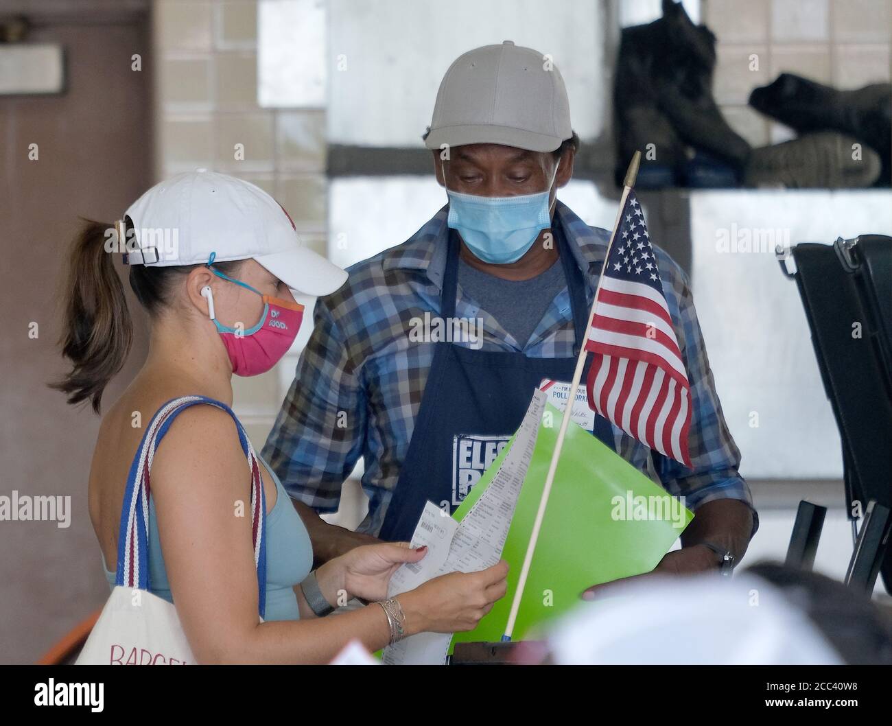 Miami, États-Unis. 18 août 2020. Une résidente de Miami en Floride remet son bulletin de vote à une employée du bureau de scrutin pour qu'elle entre dans la machine de tabulation le jour d'élection primaire pour les candidats au poste d'incendie et de sauvetage 2 de Miami, à Miami, en Floride, le mardi 18 août 2020. Les lignes aux bureaux de vote sont plus courtes et, dans certains cas, inexistantes en raison de la pandémie du coronavirus COVID-19. Photo de Gary I Rothstein/UPI crédit: UPI/Alay Live News Banque D'Images