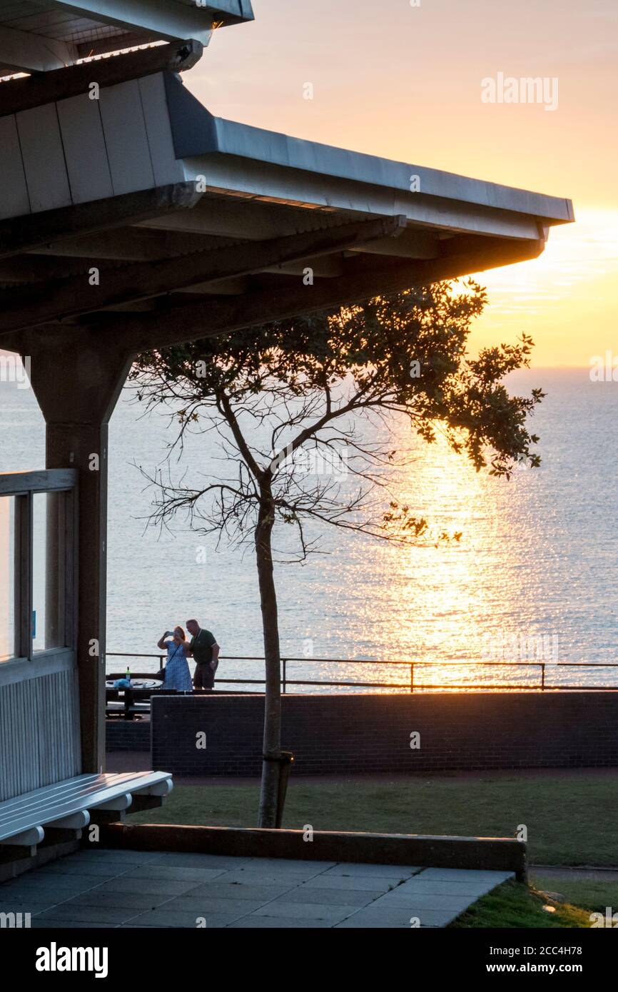 Couple prenant un selfie devant le soleil se coucher sur la mer sur la côte est à Hunstanton. Banque D'Images