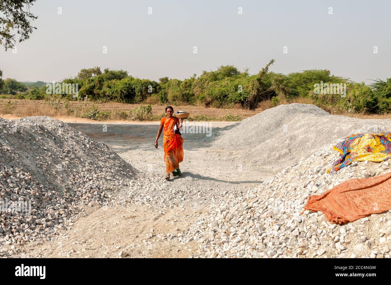 Puttaparthi, Andhra Pradesh, Inde - 11 janvier 2013 : une femme indienne marchant avec un panier de nourriture sur la pelouse du village de Puttaparthi. Banque D'Images