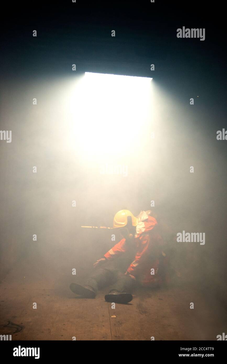Les pompiers aident les gens dans un bâtiment brûlant et fumé. Banque D'Images