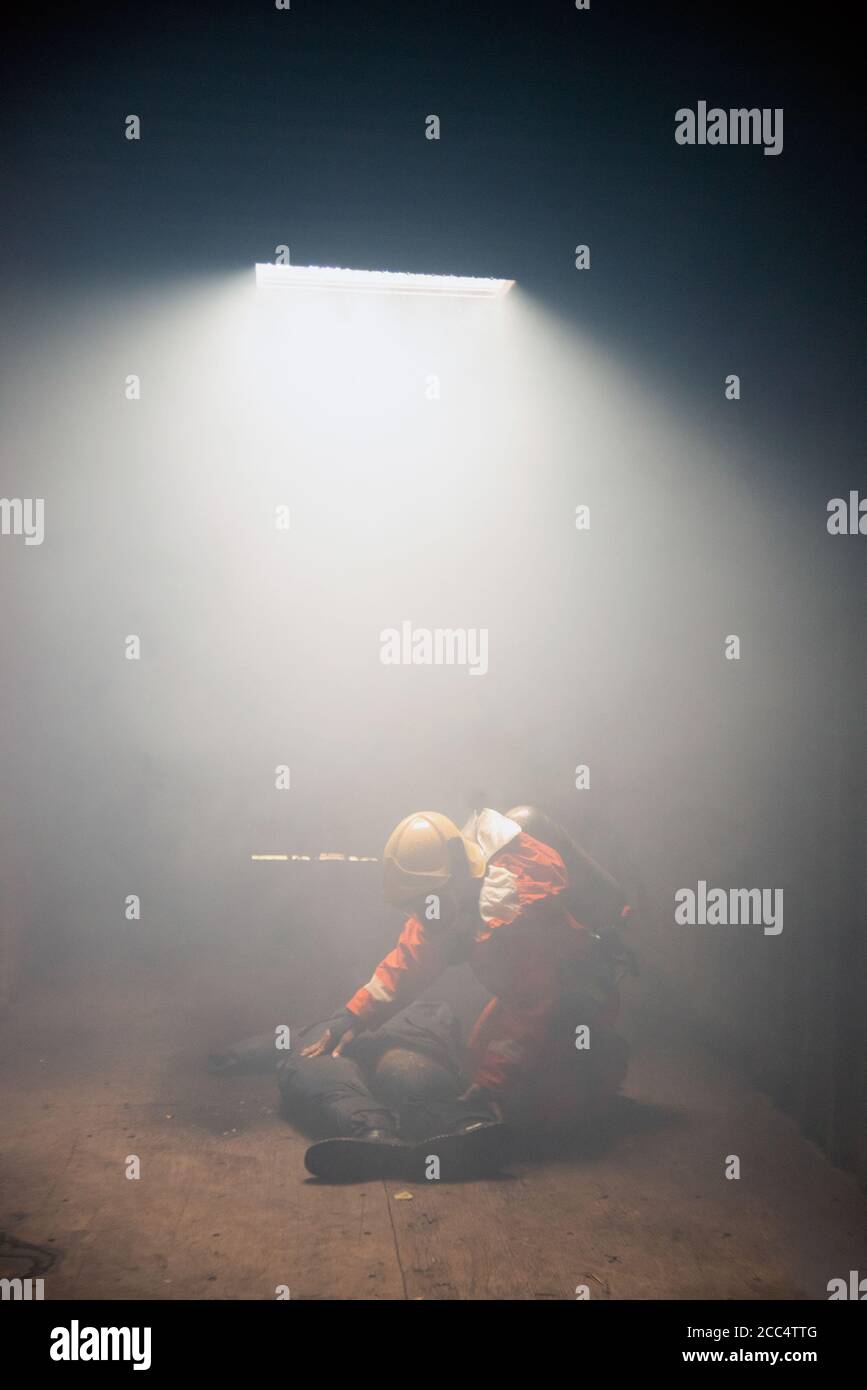Les pompiers aident les gens dans un bâtiment brûlant et fumé. Banque D'Images