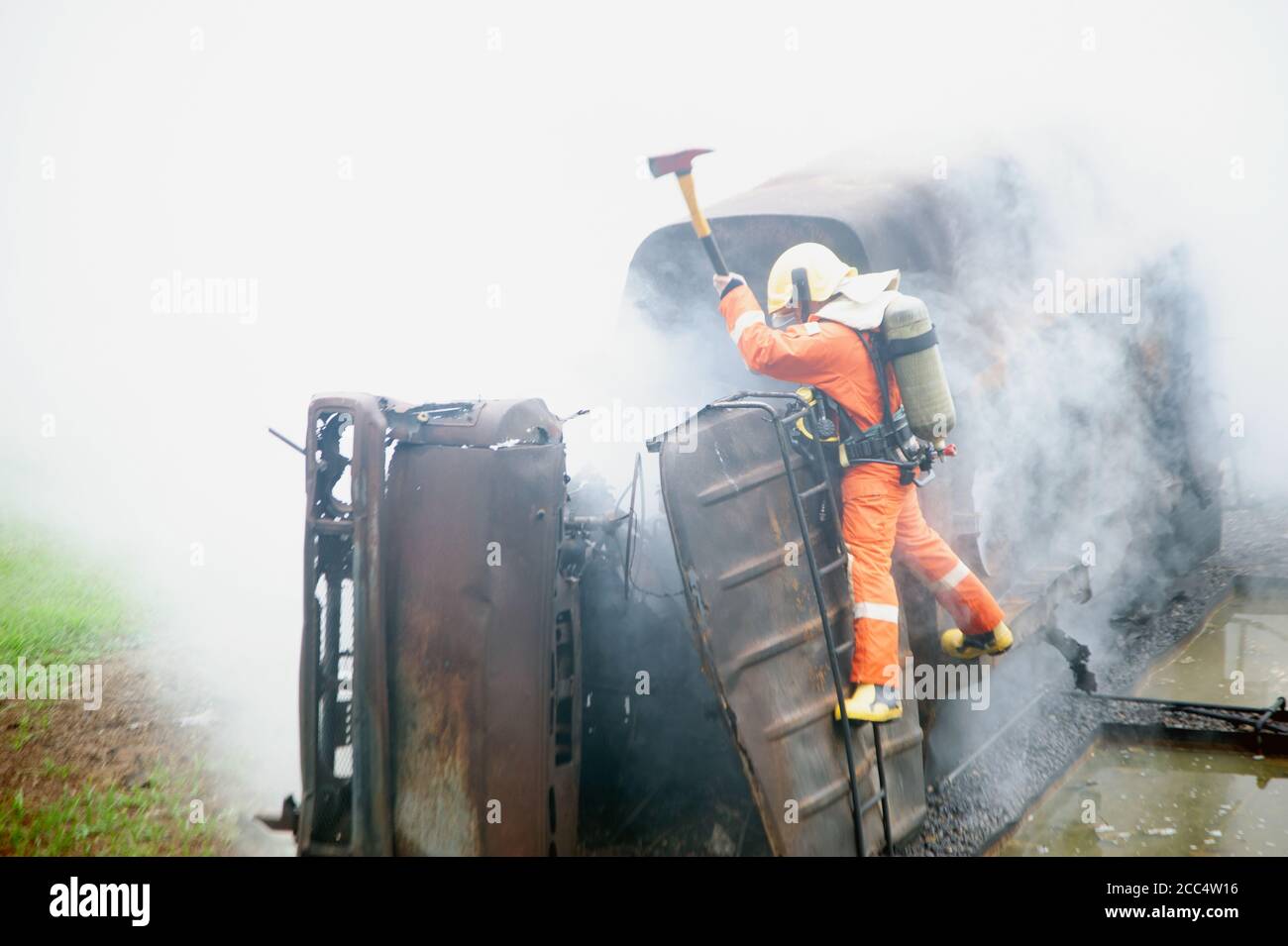 Les pompiers utilisant une hache détruisent les obstacles dans une voiture brûlante et fumée. Banque D'Images