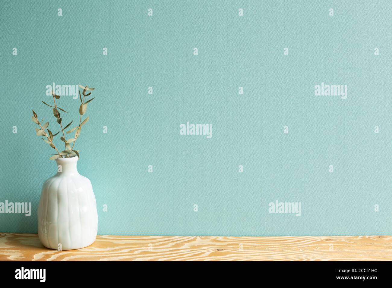 Vase de feuilles d'eucalyptus sur table en bois avec fond vert Banque D'Images