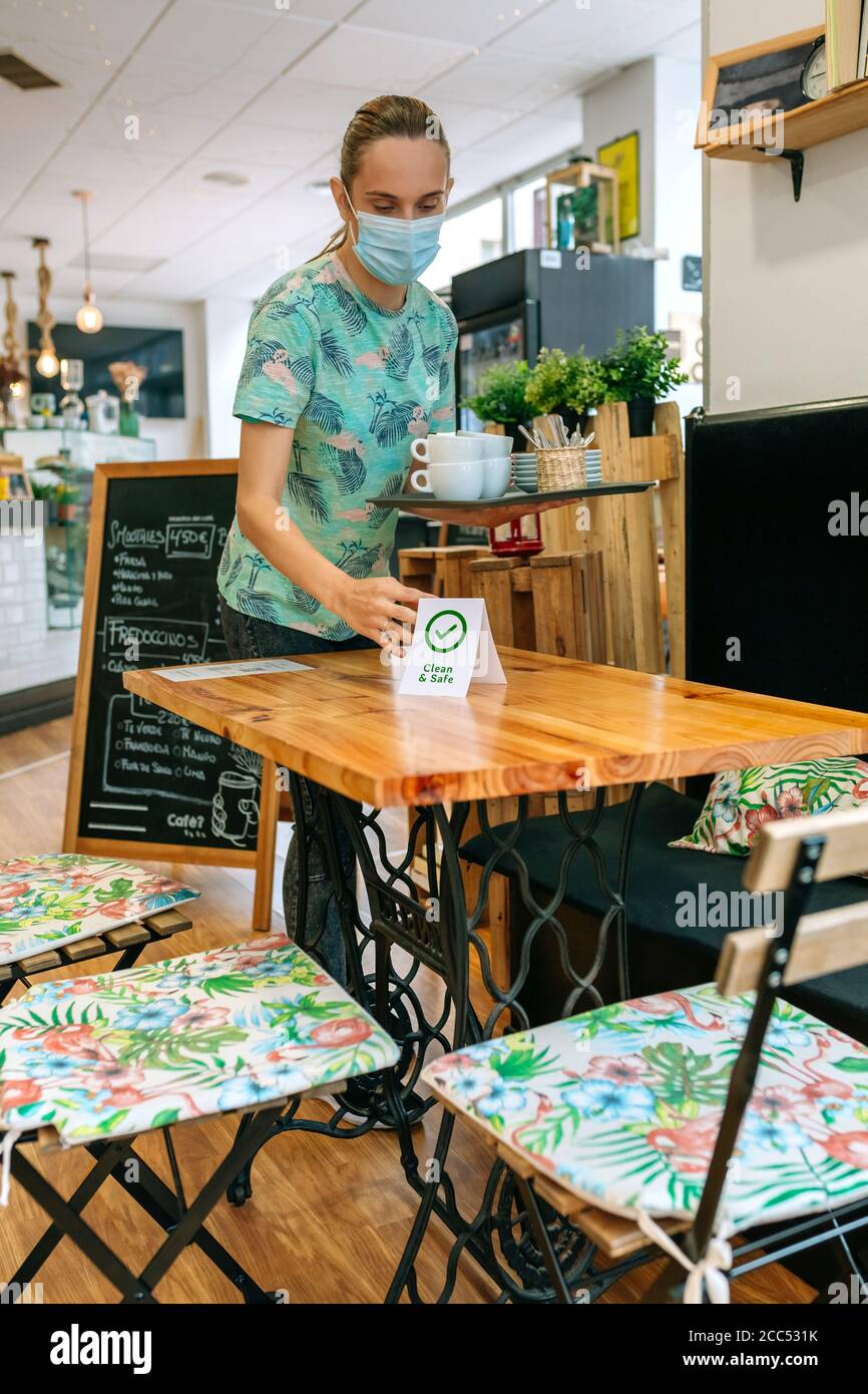 La serveuse place l'affiche sur les tables du café-restaurant Banque D'Images