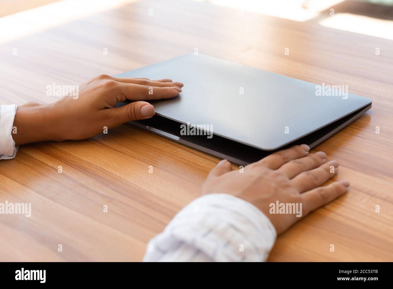 Une femme ouvre son ordinateur portable sur une table en bois Banque D'Images