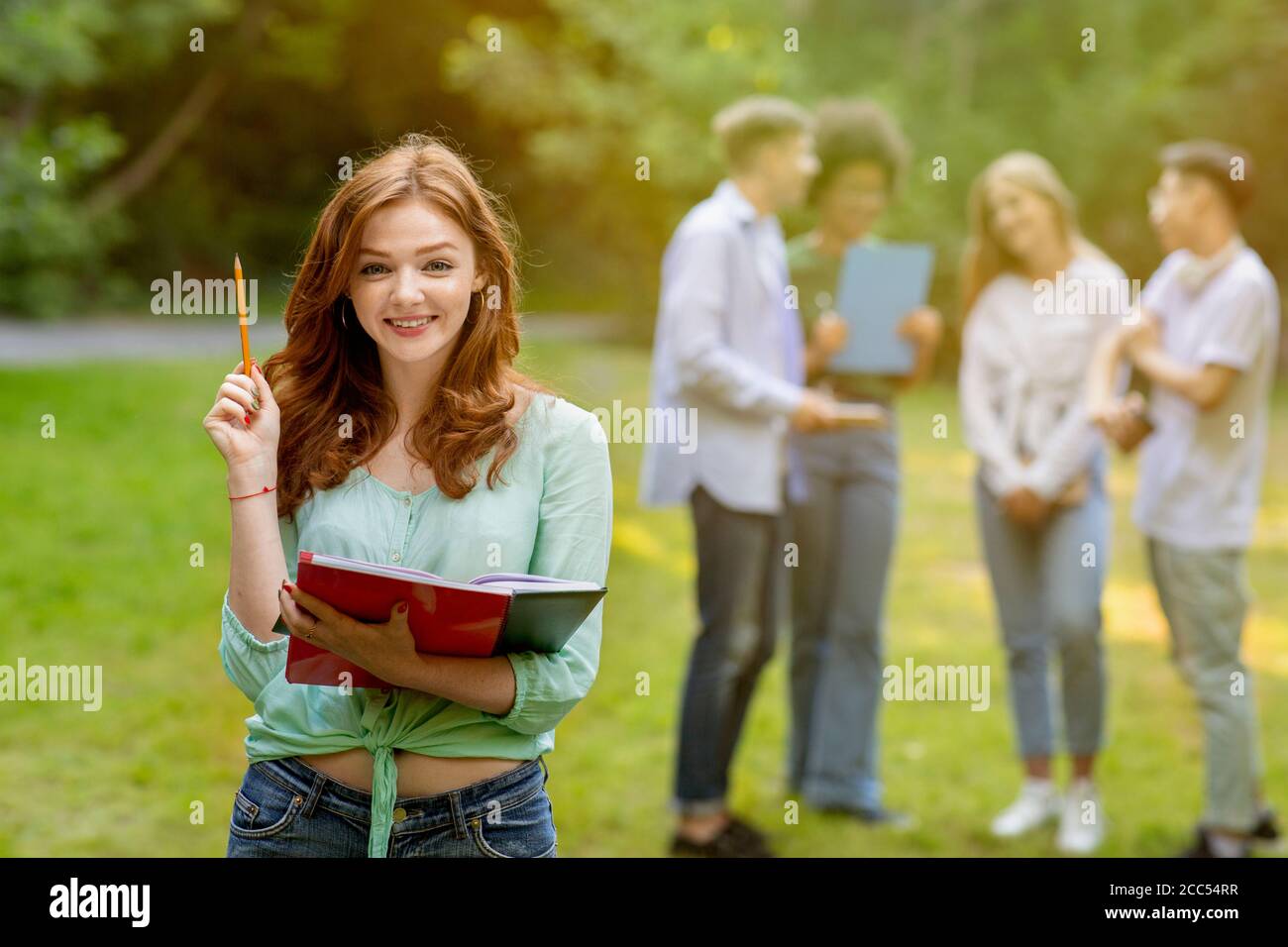 Concept d'éducation. Belle étudiante nerdy et groupe de ses camarades de classe à l'extérieur Banque D'Images