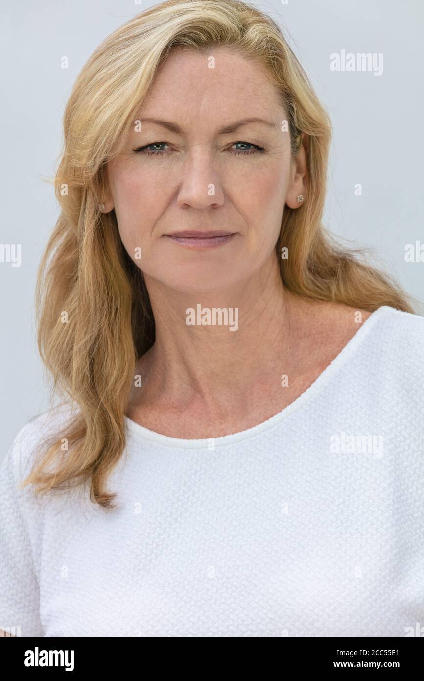 Portrait studio d'une jolie femme blonde d'âge moyen souriante sur fond blanc Banque D'Images