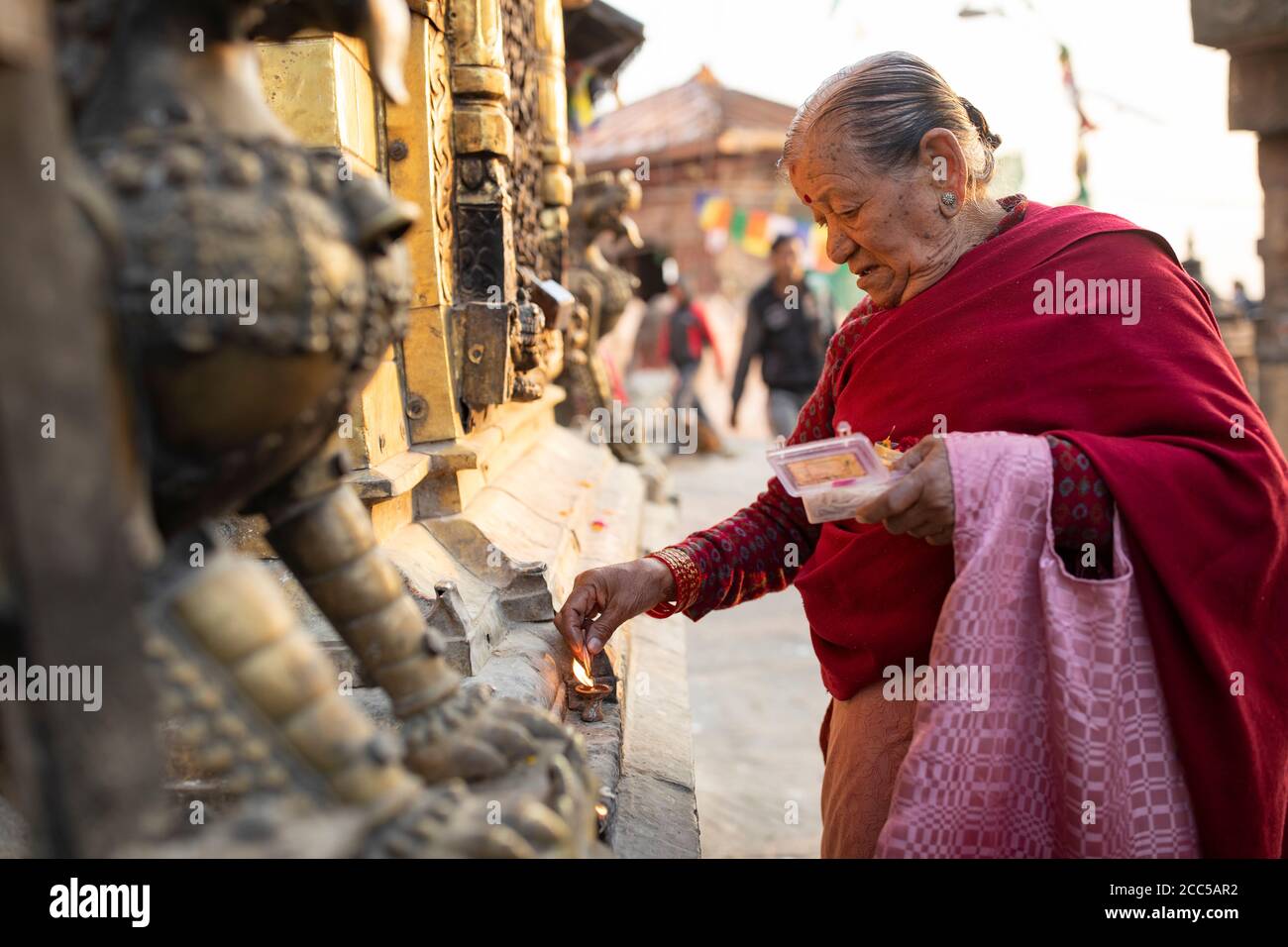 Femme allumant une bougie dans un sanctuaire à Swayambhunath stupa à Katmandou, Népal. Banque D'Images