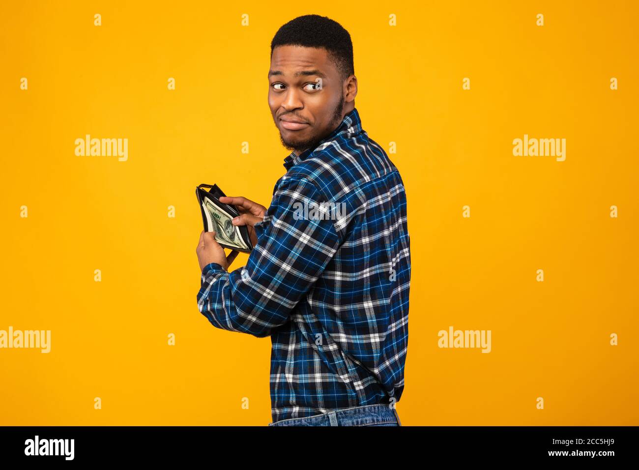 Portefeuille avec argent sur fond jaune pour homme noir sournois Banque D'Images