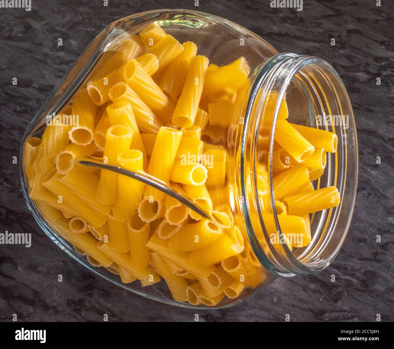 Gros plan de pâtes semoule de blé dur italien sec - rigatoni en forme de tube - dans un pot de conservation en verre. Banque D'Images