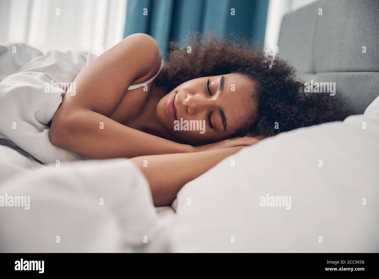 Sereine femme à tête curly couchée sur l'oreiller Banque D'Images