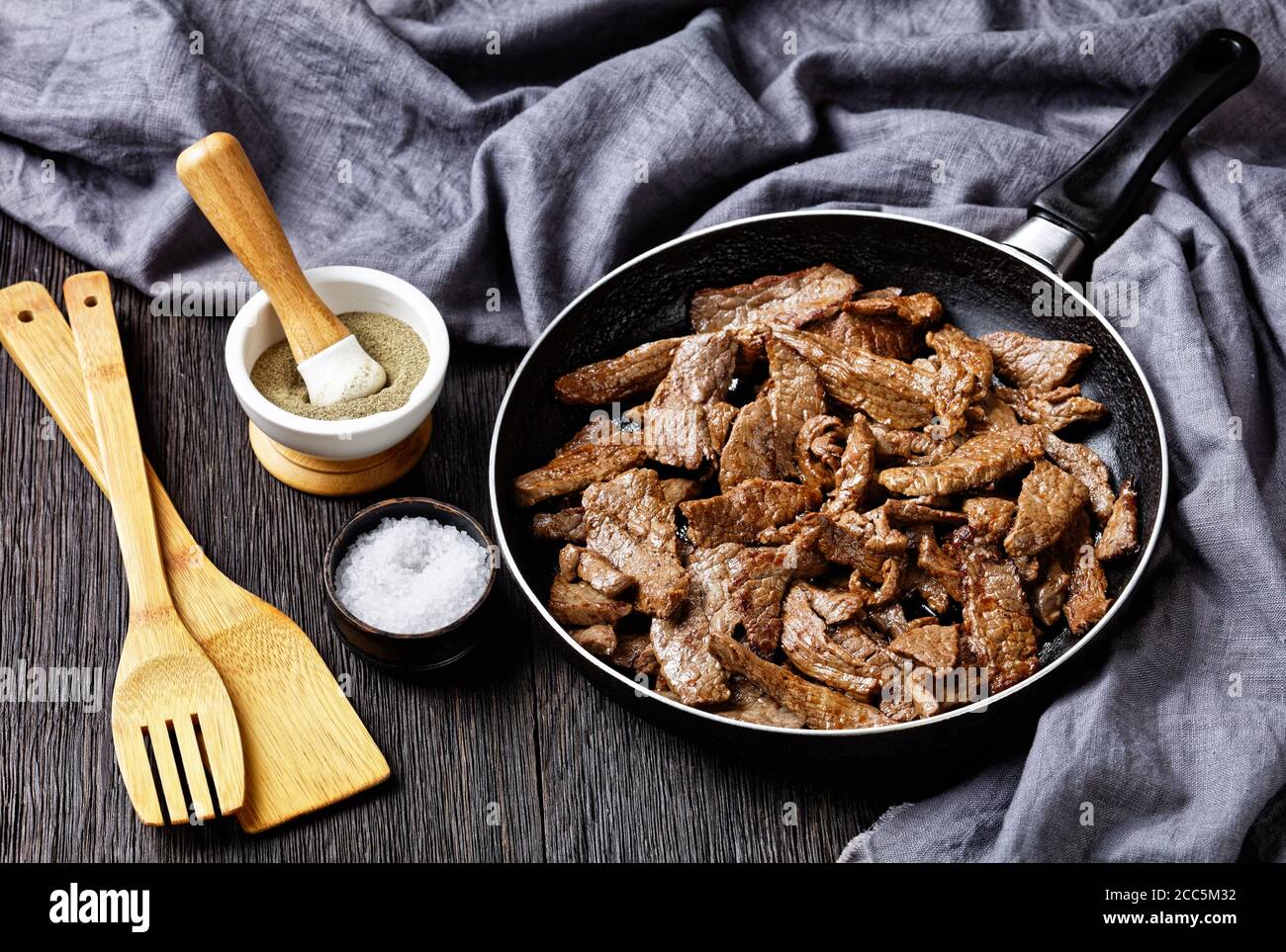 steak de bœuf ribeye frit tendre et juteux coupé en lanières, steak minute, sur une poêle sur une table en bois sombre, vue sur le paysage depuis le dessus Banque D'Images