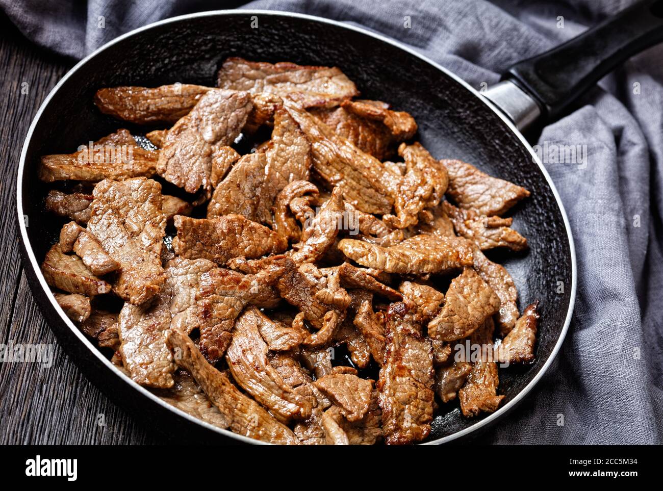 steak de bœuf ribeye frit tendre et juteux coupé en lanières, steak minute sur une poêle sur une table en bois sombre, vue sur le paysage depuis le dessus Banque D'Images