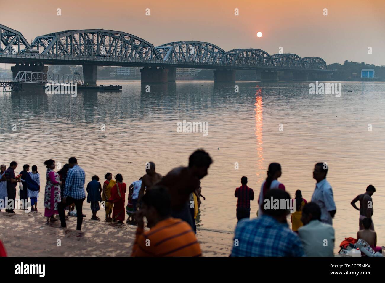 Des pèlerins hindous se rendent au Ganga Ghat de Dakshineswar le long du fleuve Hooghly avec le pont Vivekananda Setu en arrière-plan à Kolkata (Calcutta), en Inde. Banque D'Images