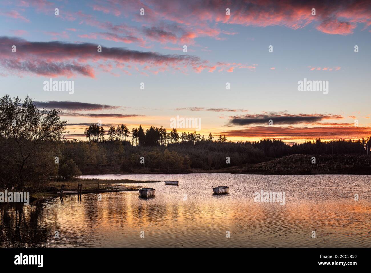 Bateaux de pêche sur le Loch Rusky au lever du soleil, un petit loch d'eau douce près de Callander dans les Highlands écossais. Banque D'Images