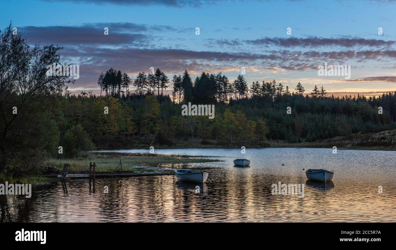 Bateaux de pêche sur le Loch Rusky au lever du soleil, un petit loch d'eau douce près de Callander dans les Highlands écossais. Banque D'Images