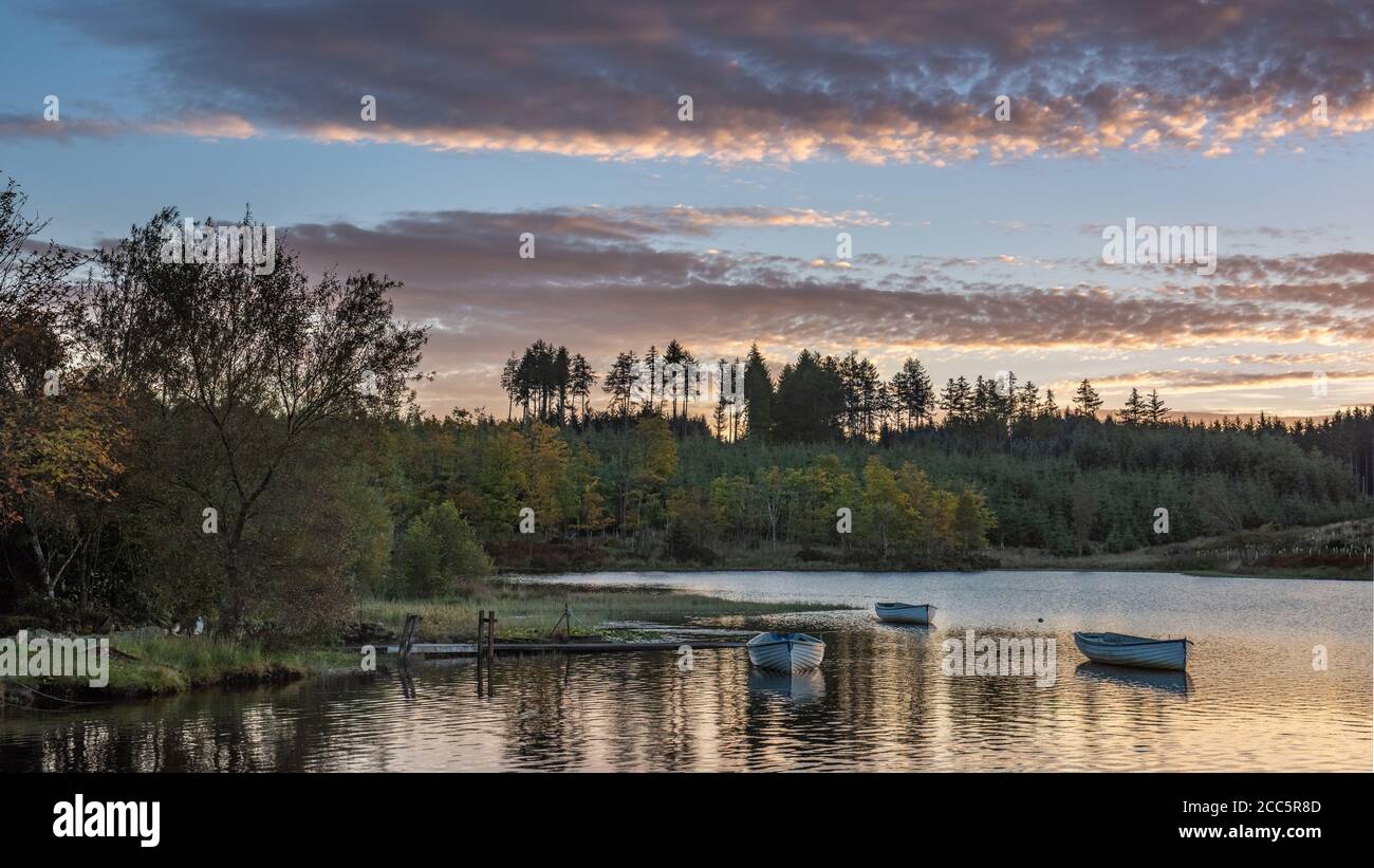 Bateaux de pêche sur le Loch Rusky au lever du soleil, un petit loch d'eau douce près de Callander dans les Highlands écossais. Banque D'Images