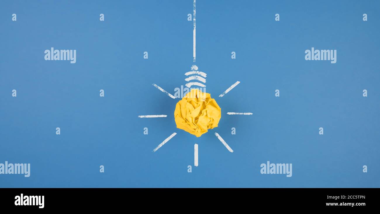 ampoule en papier jaune froissé sur fond bleu, concept d'idée et d'innovation Banque D'Images