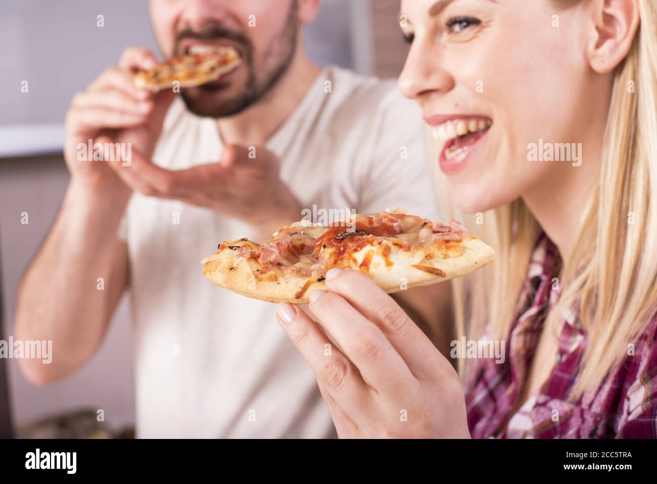 Un couple heureux de manger sa pizza maison et délicieuse dans le cuisine Banque D'Images