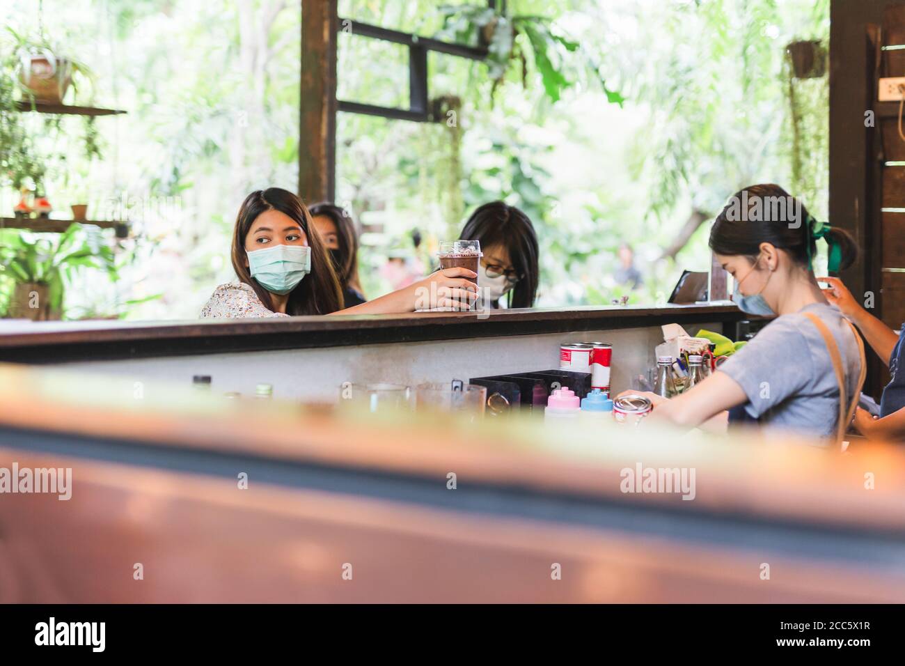 Femme Barista avec masque de protection pour faire du café pour le client dans le café Banque D'Images