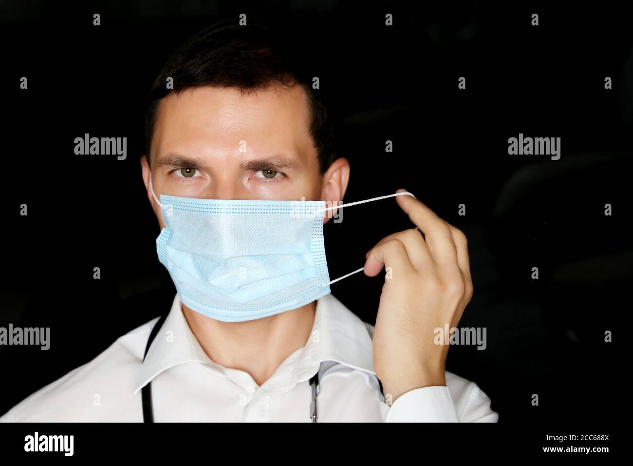 L'homme enlève le masque médical jetable. Médecin fatigué après un dur travail, concept de chirurgie ou de traitement du coronavirus Covid-19 Banque D'Images