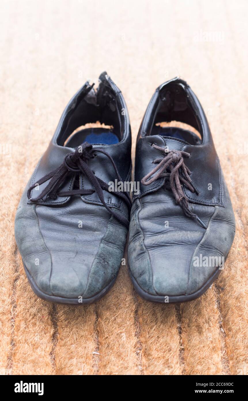 Une paire de chaussures noires très portées de pauvre avec des lacets et  des empeignes sans égal qui sont éloignés de la semelle Photo Stock - Alamy