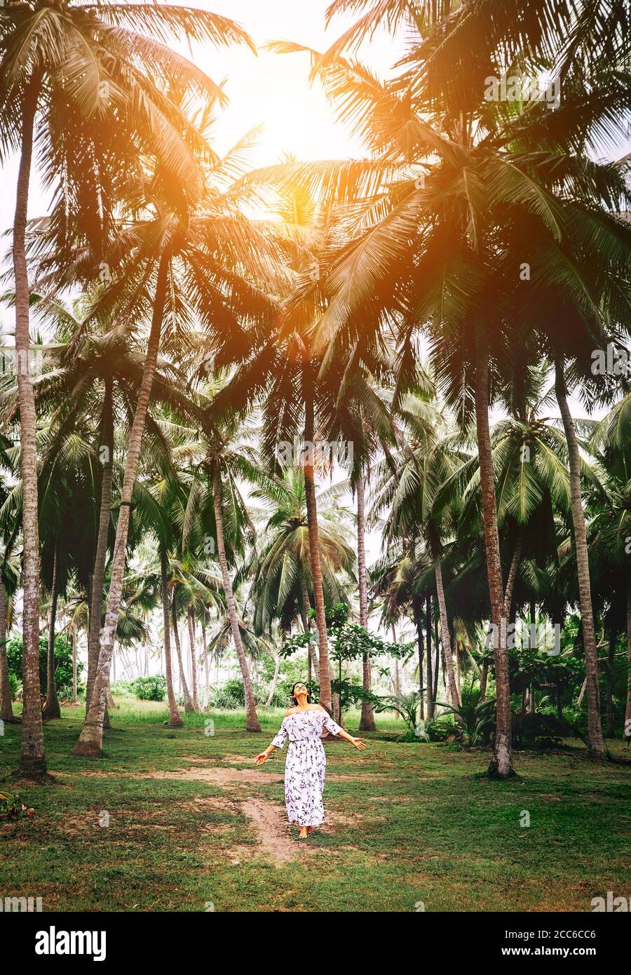 Femme en robe longue marcher sous les palmiers. Vacances romantiques sur l'île Banque D'Images