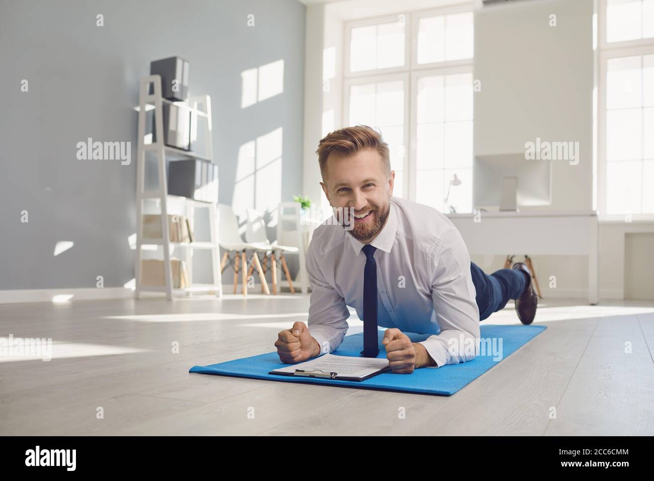 Homme d'affaires faisant des exercices de sangle d'abs tout en restant au bureau. Banque D'Images