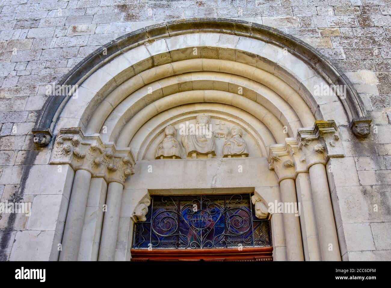 Portail médiéval de l'église Saint Geraud, sculpture de Jésus Christ couronné entourée de la Vierge Marie couronnée et de Saint Jean le Baptiste, XIIe siècle, Banque D'Images