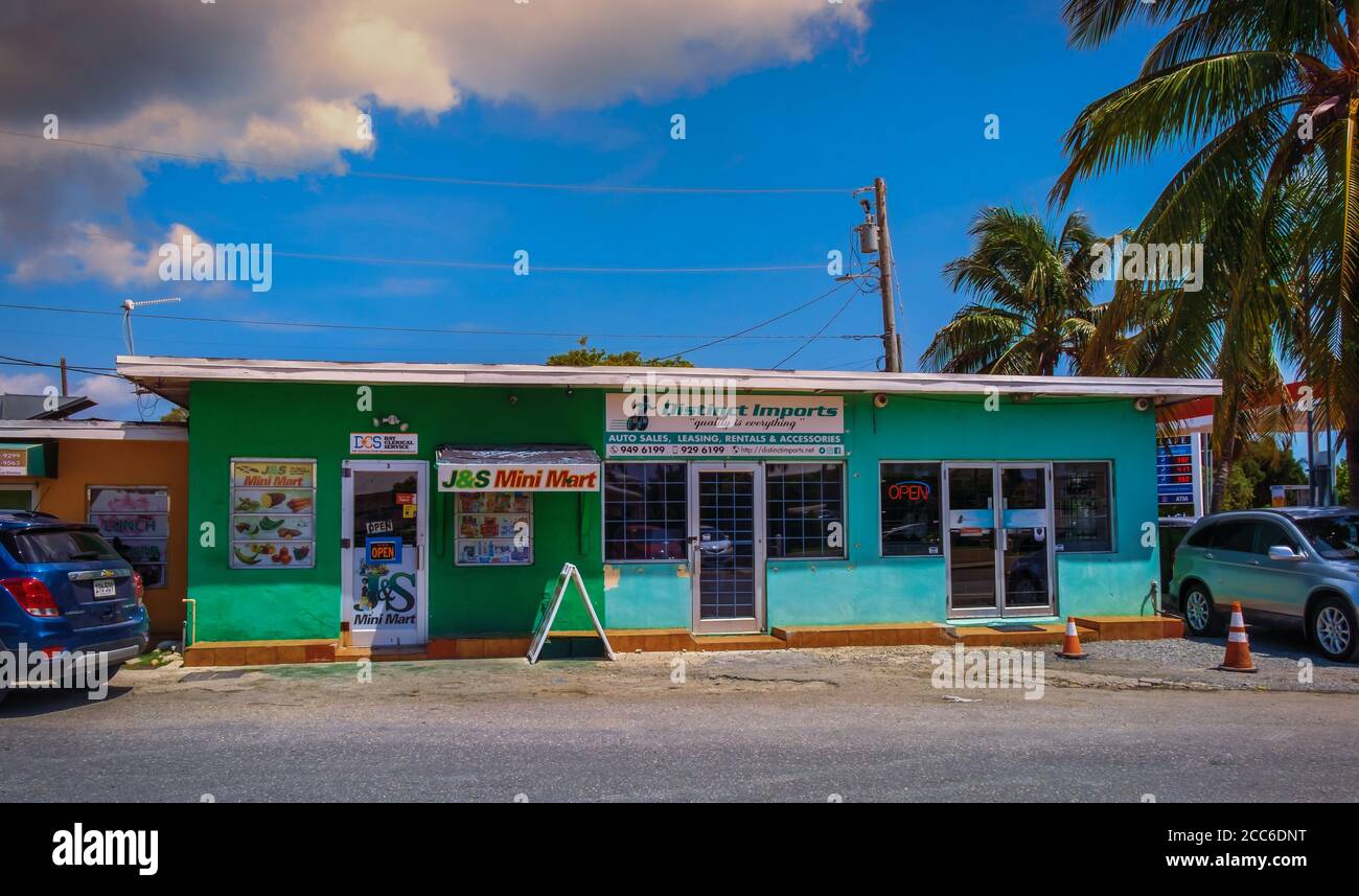 Grand Cayman, îles Caïmans, juillet 2020, vue sur un petit magasin d'alimentation et un bureau de vente de voitures dans un bâtiment coloré à George Town Banque D'Images